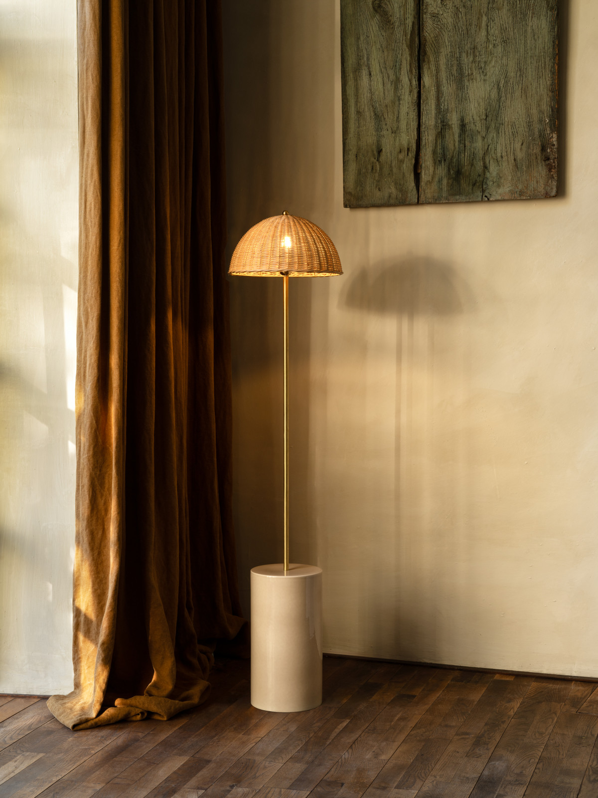 Vincent Sheppard Arvin Stehlampe mit natürlichem Rattanschirm, Messingstab und Keramikfuß in Mushroom-Farbe, die ein warmes Licht in einem eleganten Interieur verbreitet.