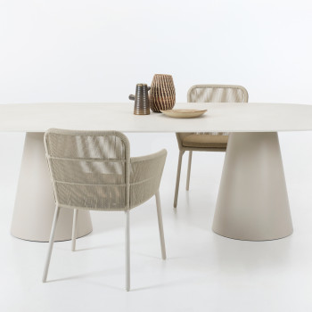 Vincent Sheppard Akari eetkamerstoelen met gevlochten zitting en metalen frame, gecombineerd met de Sandro eettafel met een afgerond blad en twee kegelvormige sokkels in een neutrale afwerking.