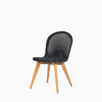 Damien chair by Vincent Sheppard with a black seat and teak base, displayed in a studio setting.