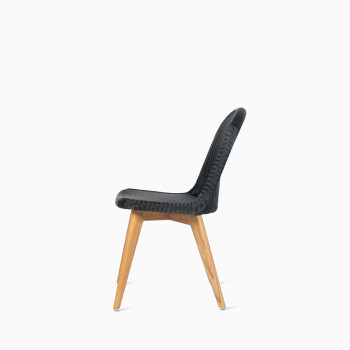 Side view of Vincent Sheppard’s Damien chair with a black seat and teak base, shown in a studio setting.