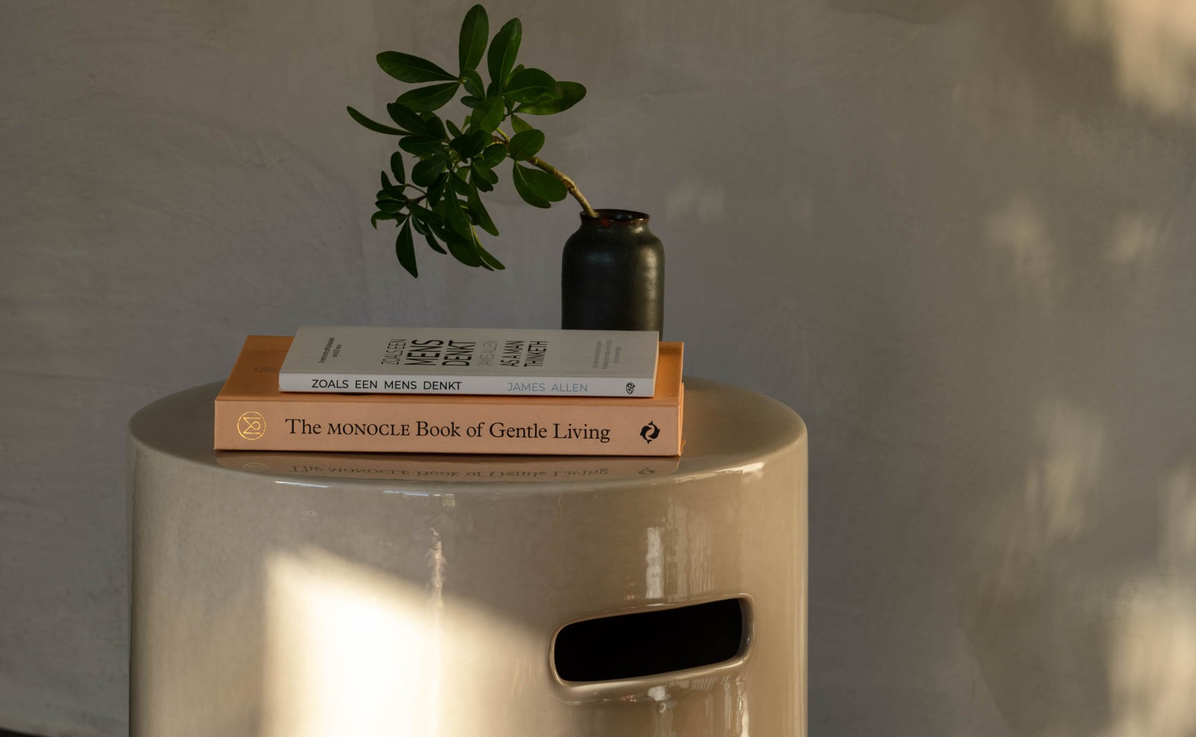 Arvin Stool by Vincent Sheppard in Mushroom finish with books and a ceramic vase on top