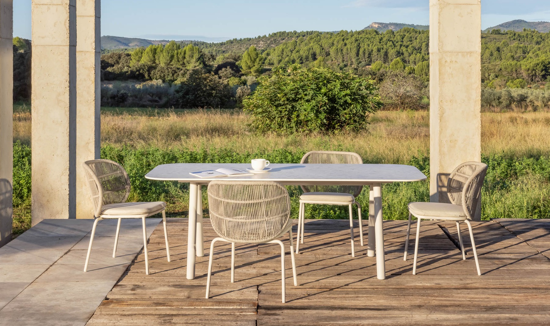Vincent Sheppard Kodo dining table Shards with Kodo dining chairs in Dune White on terrace with landscape