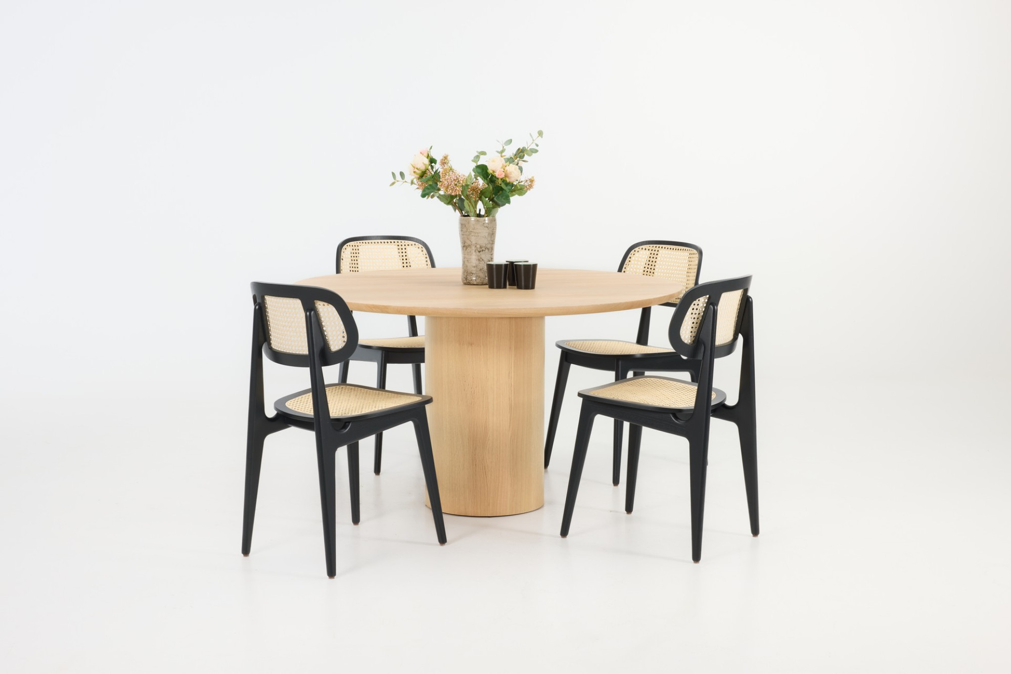 Vincent Sheppard Atlas round dining table in natural oak with Titus Lloyd Loom dining chairs in Black.